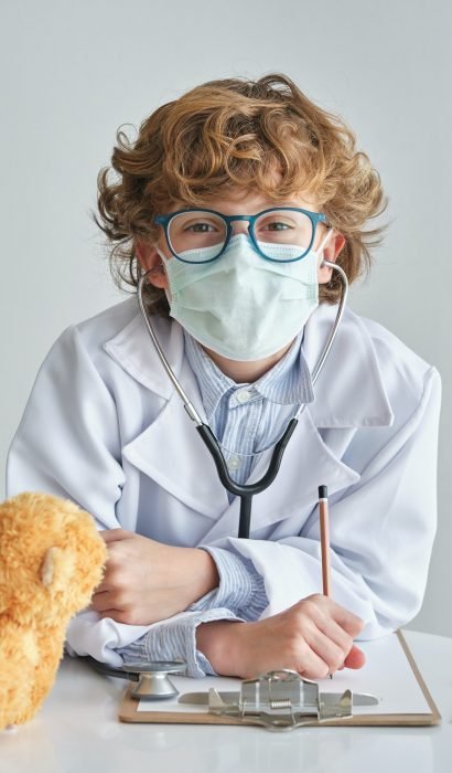 Boy doctor in sterile mask with stethoscope and toy bear