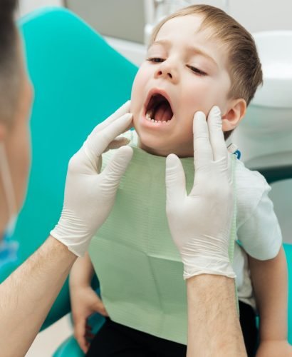 Dentist examining teeth of little boy witting with mouth opened
