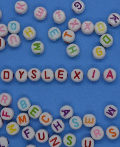 Dyslexia, n red letters, surrounded by random alphabet letters on a blue background with copy space