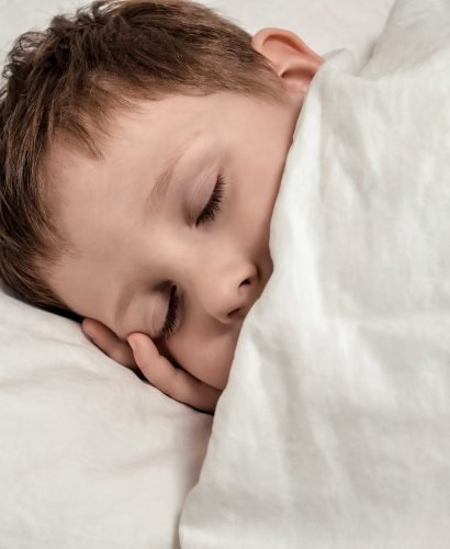 Sleeping young boy in white bed